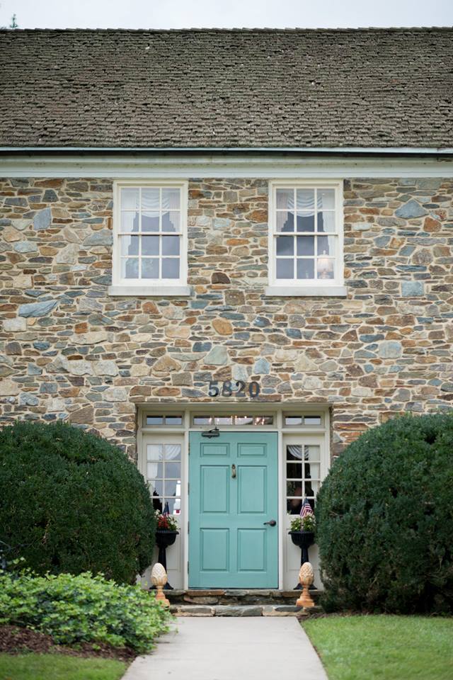 A turquoise door contrasts with stone walls of the Stone Manor 