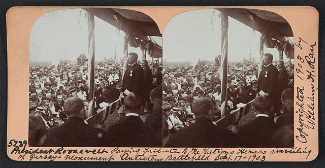 A black and white stereograph showing Teddy Roosevelt addressing a crowd at Antietam
