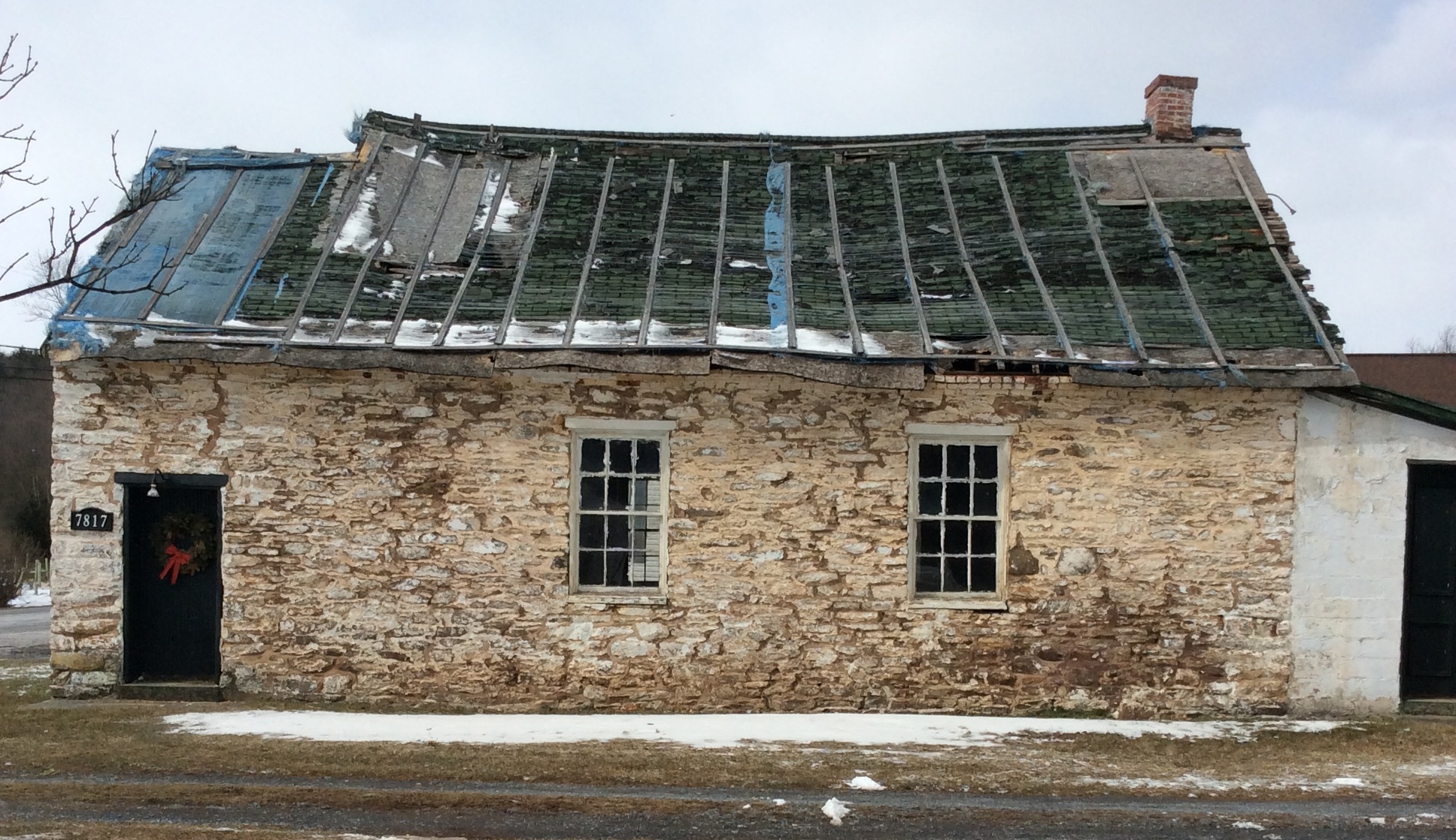 The roof and stone walls of the Rocky Spring Schoolhouse are obviously sloping, in need of repair.